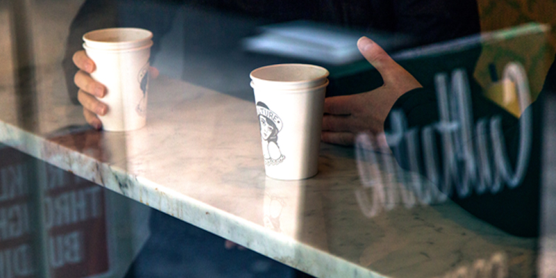 Two Men Sit at a Bar in a Coffee Shop With Their Two Coffee Cups