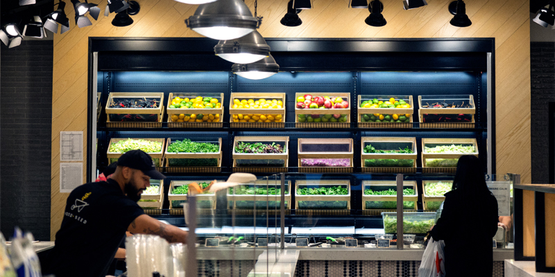 A Woman Tries to Decide Her Food Order From Crates of Fresh Fruits and Vegetables at a Restaurant