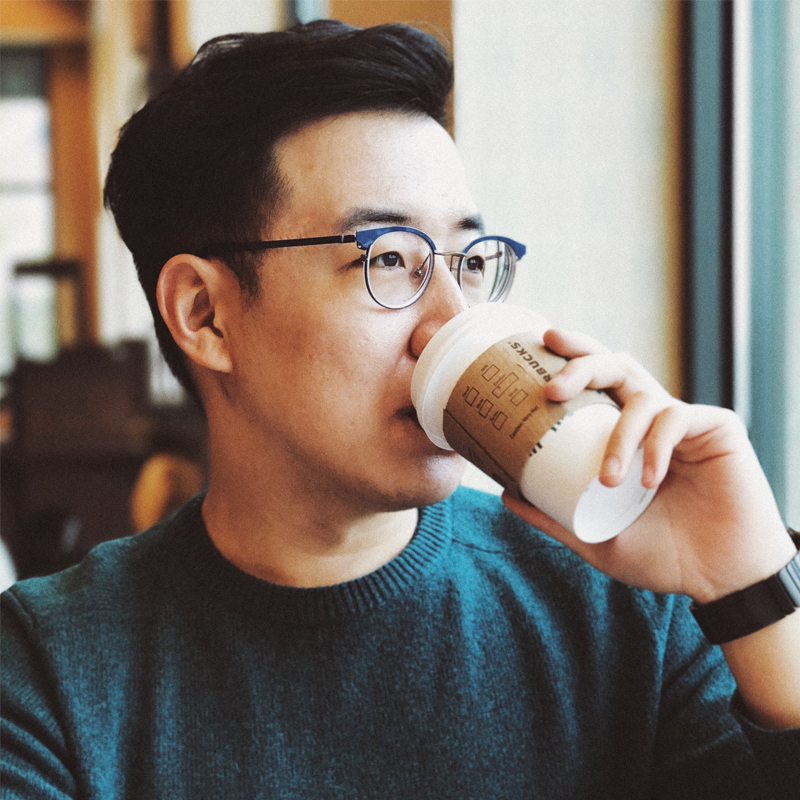 Young Asian Man With Glasses Drinks From Starbucks Coffee Cup