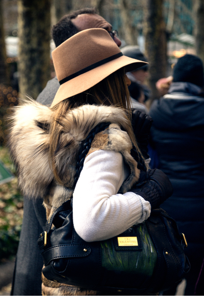 Stylish Woman in Brown Floppy Hat With Fur Vest Stands With African American Man on Sidewalk